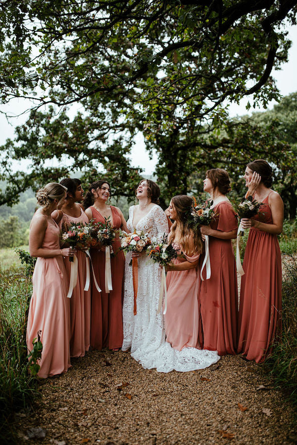 Bridal Party smiles at bride, wearing shades of pink and orange